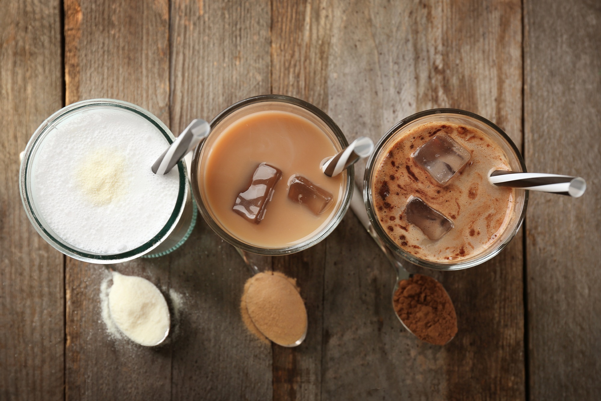 Three glasses of powdered drinks with milk, tea and cocoa powders